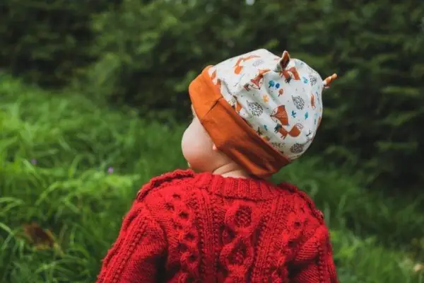 Vue arrière d'un bonnet aux oreilles de chat porté par une petite fille, avec un motif de petits animaux de la forêt.