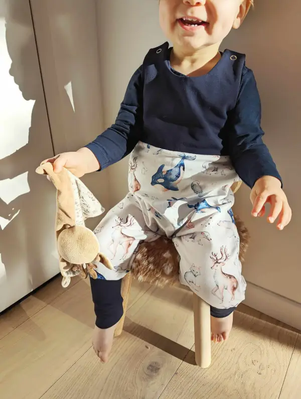 Bébé souriant avec sa salopette Animaux Polaires, motif inspiré de la nature et des animaux du froid.
