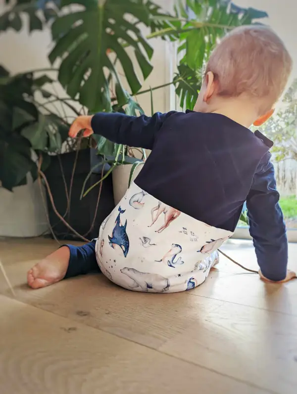 Petit garçon assis de dos avec une salopette Animaux Polaires, en coton bio certifié, pour un look unique et éthique.