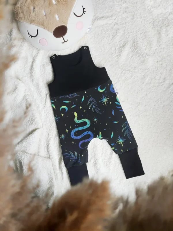 Salopette évolutive en coton bio, taille 3-12 mois, motif Serpent Magique (serpent bleu, vert, jaune, feuillages, lunes, étoiles) avec un uni noir, pour un look original et magique.
