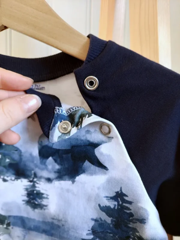 Zoom sur les pressions à l’encolure du sweat évolutif motif Paysage d’Hiver.